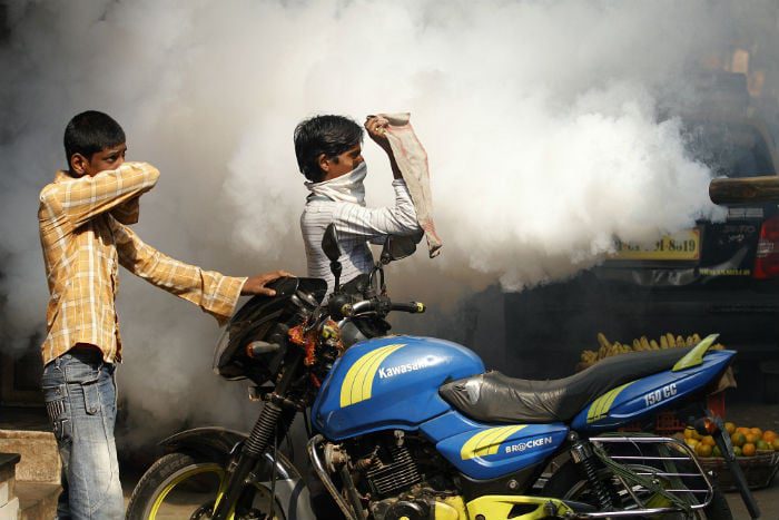People try to protect themselves from the smoke as a truck fumigates