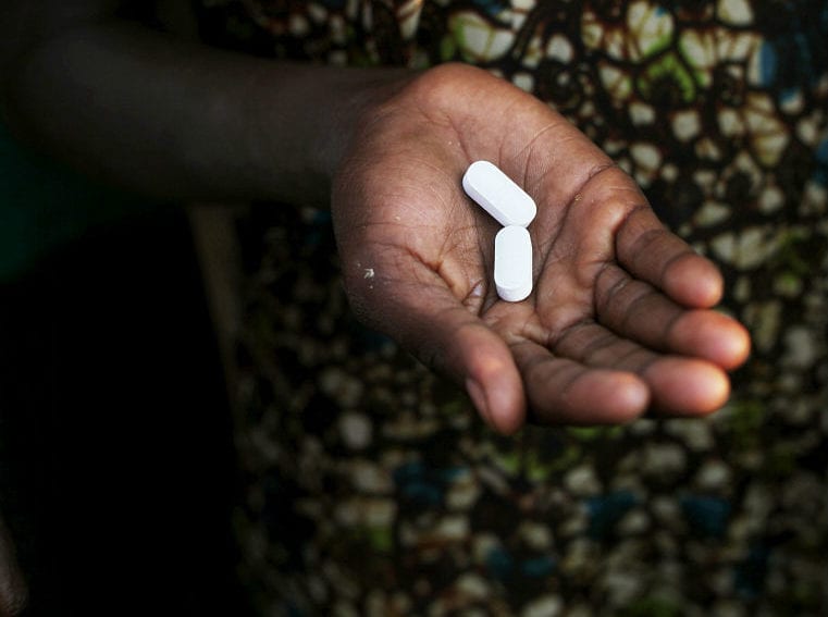woman holds some of the drugs she needs to take