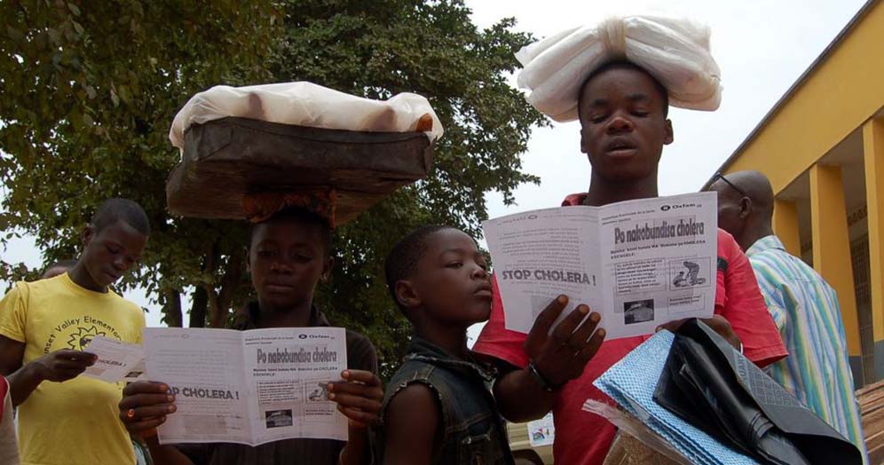 Children reading cholera-prevention leaflets warning about the dangers of cholera and how it can be prevented. Copyright: Oxfam (CC BY 2.0)
