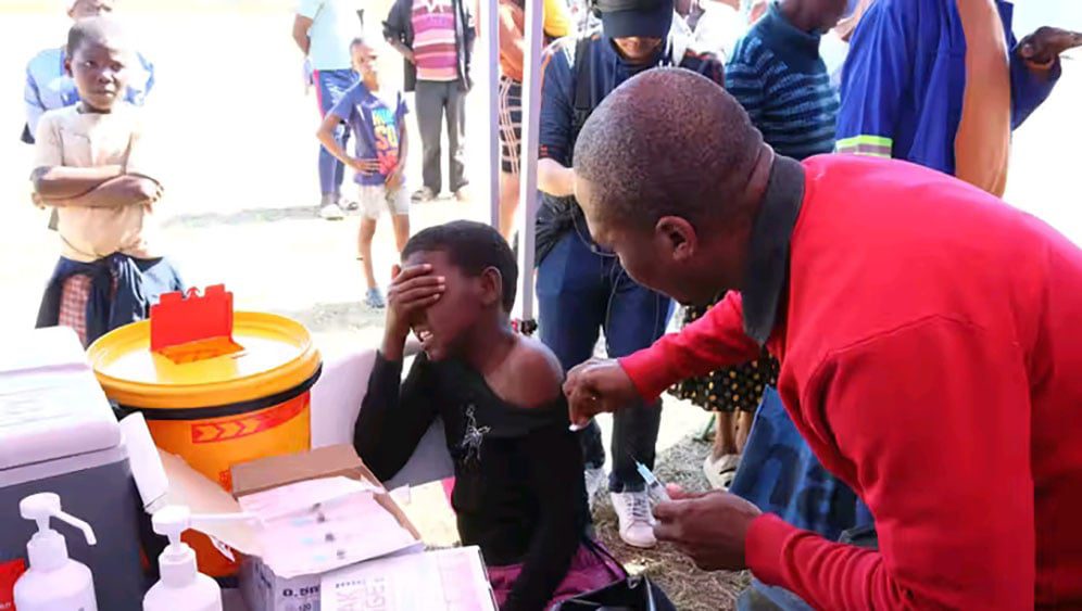Female patient reacts as a male nurse prepares to inject her.