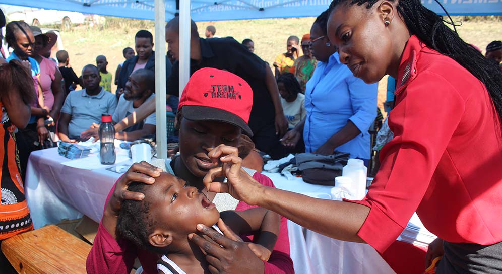 Mother holds her child as anurse administer a shot.