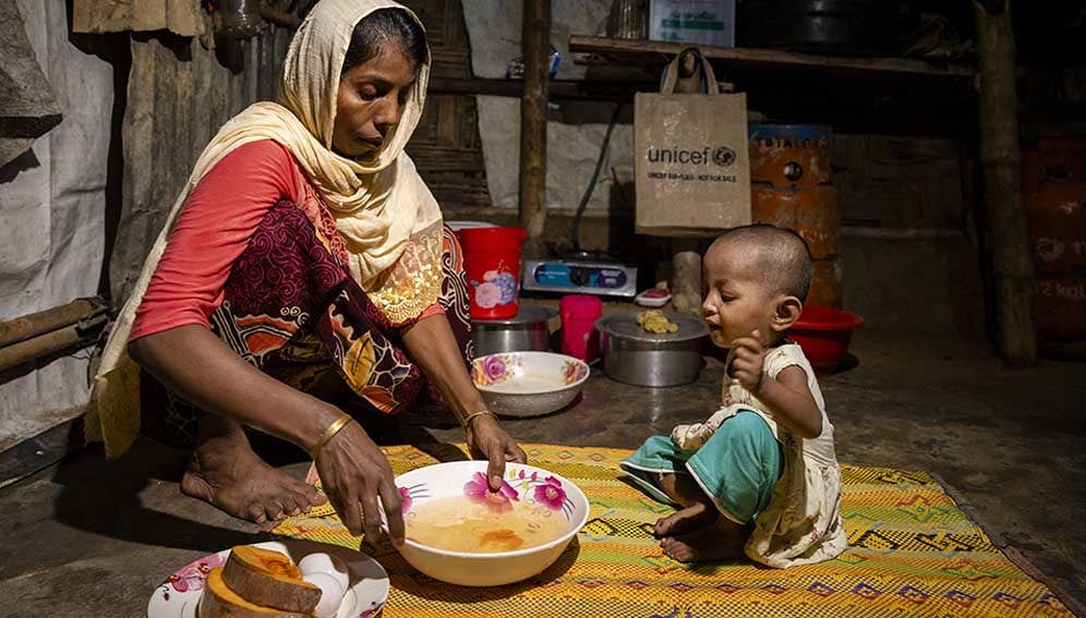 On 16 July 2024, Rubeda, 28, prepares a meal for her daughter Sofiba, 2, who suffers from severe acute malnutrition, at their shelter in the Rohingya refugee camps in Cox’s Bazar, Bangladesh.