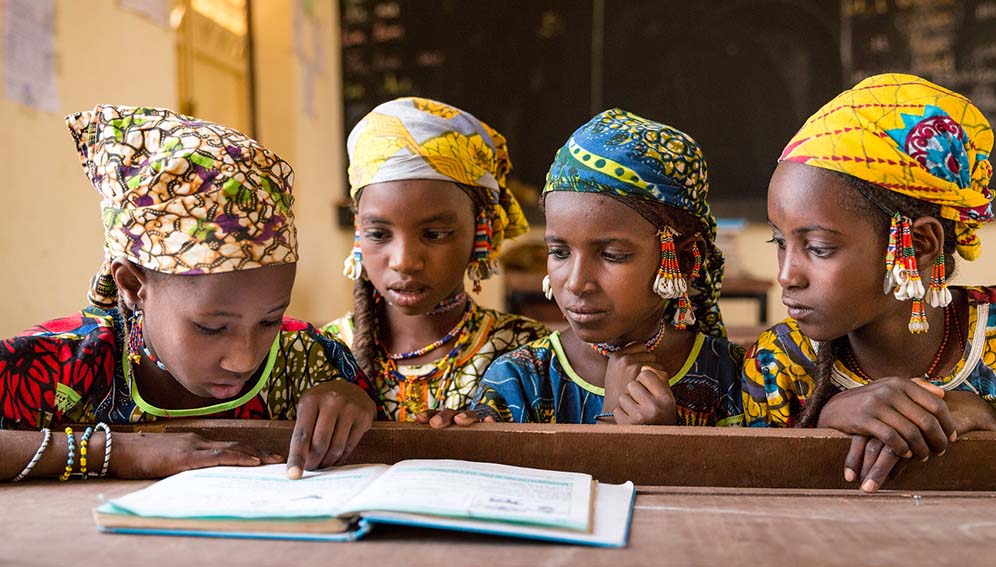 Fulani girls share a textbook. Despite being in class three, these girls cannot read more than a few words in the textbook. The teacher prompts them, word by word. It is a given that learning outcomes are affected when students have to share a textbook among four students, but this is not a textbook issue. It is a language issue. Niger’s traditional primary school curriculum—in which students learn in French throughout their school careers under teachers who speak French, but not the local language—is the real issue. Photo credit: GPE/Kelley Lynch