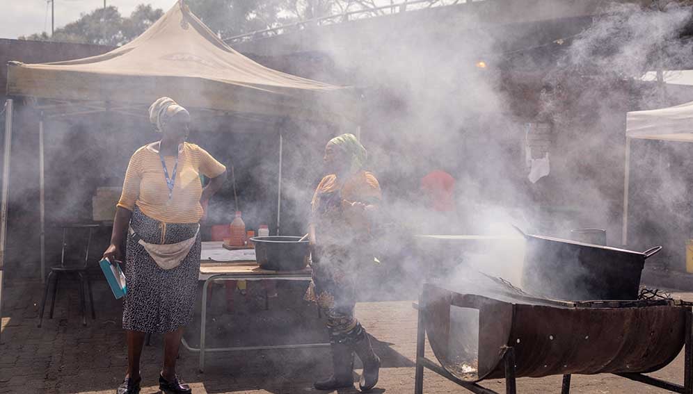 People cook on open fires outside the Kwa Mai-Mai Market in Johannesburg, South Africa, on November 22, 2023.